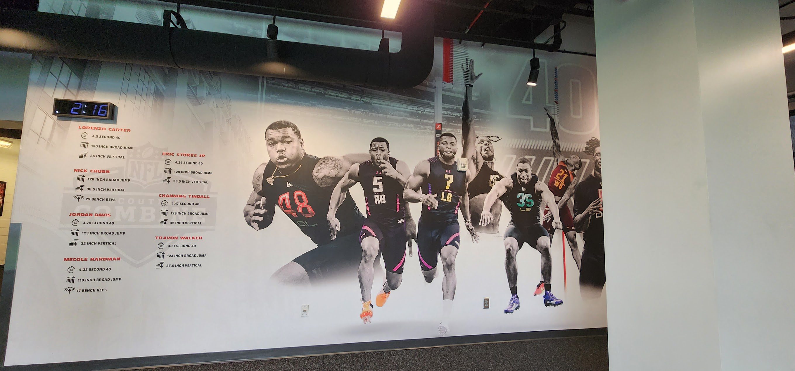 A large mural of athletes in black and red uniforms.