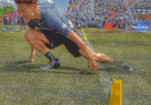 Athlete sprinting through agility course outside.